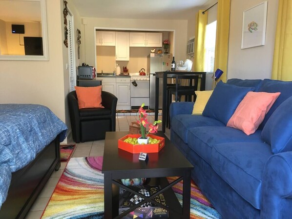 A living room with two sofas, a coffee table with a flower vase, and a kitchen in the background.