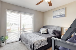 A bedroom with a bed, a ceiling fan, a window with blinds, a bedside table, and a potted plant. - BEAUTIFUL RESORT LAKEHOUSE! (Montgomery)