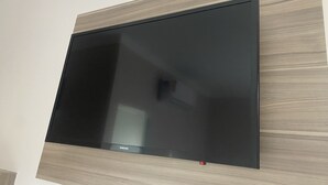 A flat-screen TV mounted on a wall with a wooden panel design. - Hotel prime (São Paulo)