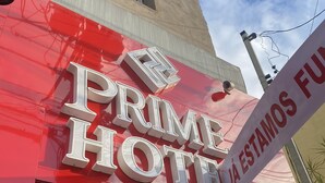 A hotel sign with the name "PRIME HOTEL" and a partially visible sign that says "JA ESTAMOS FU". - Hotel prime (São Paulo)