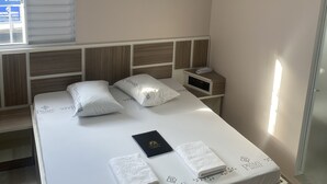 A hotel room with a bed, bedside table, and an air conditioning unit. - Hotel prime (São Paulo)