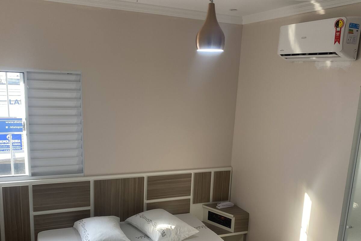 Ein Hotelzimmer mit einem Bett, einem Nachttisch und einer Klimaanlage.