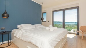 A modern bedroom with a large bed, a small table, a chair, and a view of the outdoors. - Gorgeous home in Sibenik (Sibenik)