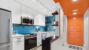 Een moderne keuken met witte kasten, een roestvrijstalen oven, een magnetron en een blauwe tegelachterwand.