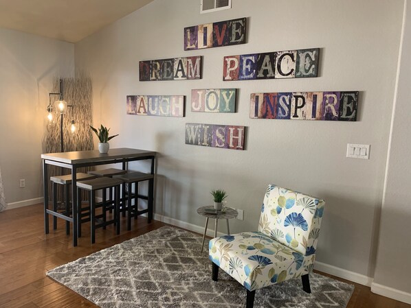 A cozy dining area with a wooden table and chairs, a patterned rug, and a decorative wall with inspirational words. - 3 King Beds, Heated Pool!! (Mesa)