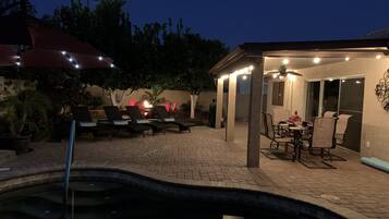 A patio area with a pool, outdoor seating, and a covered dining area.