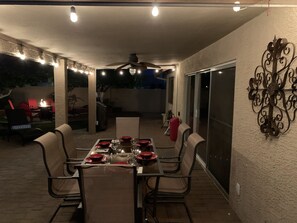 An outdoor patio with a table set for dining, surrounded by chairs, and a decorative wall piece. - 3 King Beds, Heated Pool!! (Mesa)