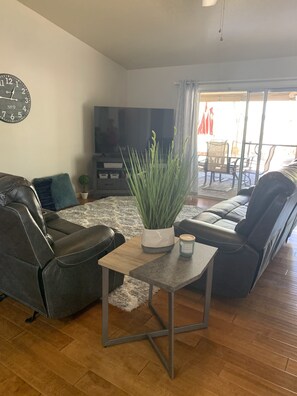 A living room with a sofa, a coffee table, a TV, and a plant. - 3 King Beds, Heated Pool!! (Mesa)