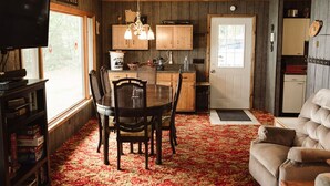 A cozy cabin interior with a dining area, kitchen, and a comfortable seating area.