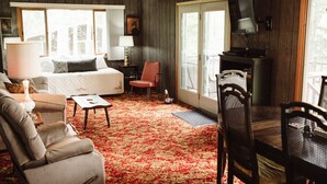 A cozy room with a bed, a TV, a dining table, and a red carpet.