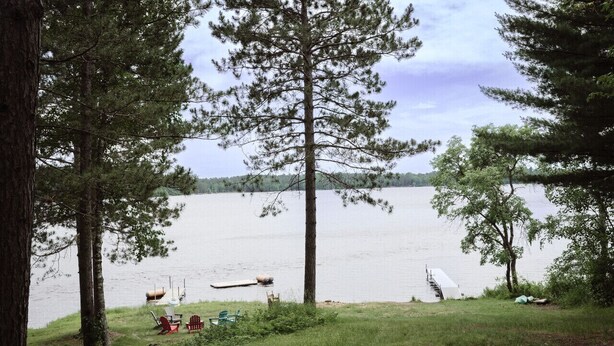 A lakeside view with a grassy area, a hammock, and a canoe.