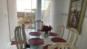 A dining area with a glass table, red placemats, and wooden chairs. - Pé na areia. (Arraial do Cabo)