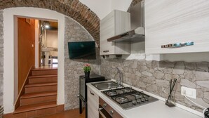Una cocina moderna con un arco de piedra, un televisor montado sobre la estufa y una escalera que lleva a otra habitación.