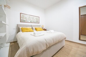 Une chambre d’hôtel avec un lit, un tableau, une table de chevet et un miroir.