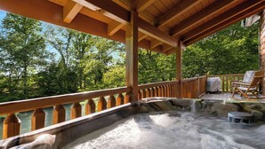 Ein Whirlpool mit einer Holzterrasse und Blick auf einen Fluss und Bäume.