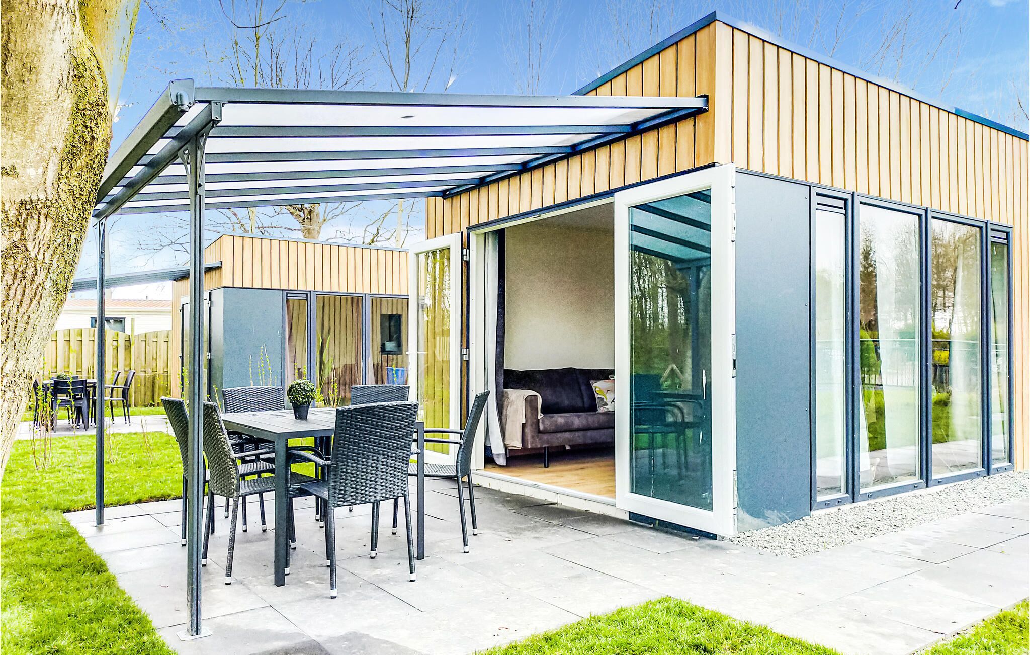 Een modern huis met een overdekte patio, een eethoek en een woonkamer met een bank en een tafel.