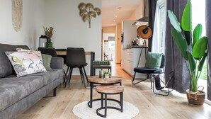 Una sala de estar moderna con un sofá gris, una mesa de centro de madera y un comedor con mesa y sillas.