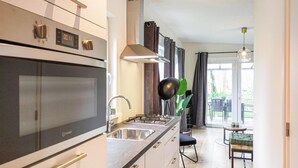 Una cocina moderna con electrodomésticos de acero inoxidable, un lavamanos y una zona de comedor con mesa y sillas.