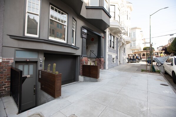 A modern building with a garage door, a brick entrance, and a wooden planter with cacti.
