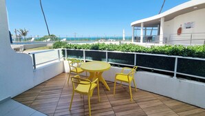 A balcony with a wooden floor, yellow chairs, and a round table.