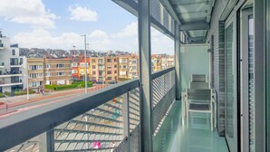 Un balcon offrant une vue sur le paysage urbain, avec des immeubles résidentiels à plusieurs étages et un ciel dégagé.
