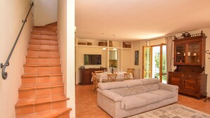 A staircase with terracotta tiles, a dining area with a table and chairs, a sofa, and a cabinet with glass doors. - Lovely home in Toffia (Toffia)