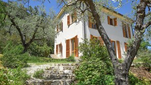 A two-story building with a white facade and wooden shutters, surrounded by lush greenery and olive trees. - Lovely home in Toffia (Toffia)