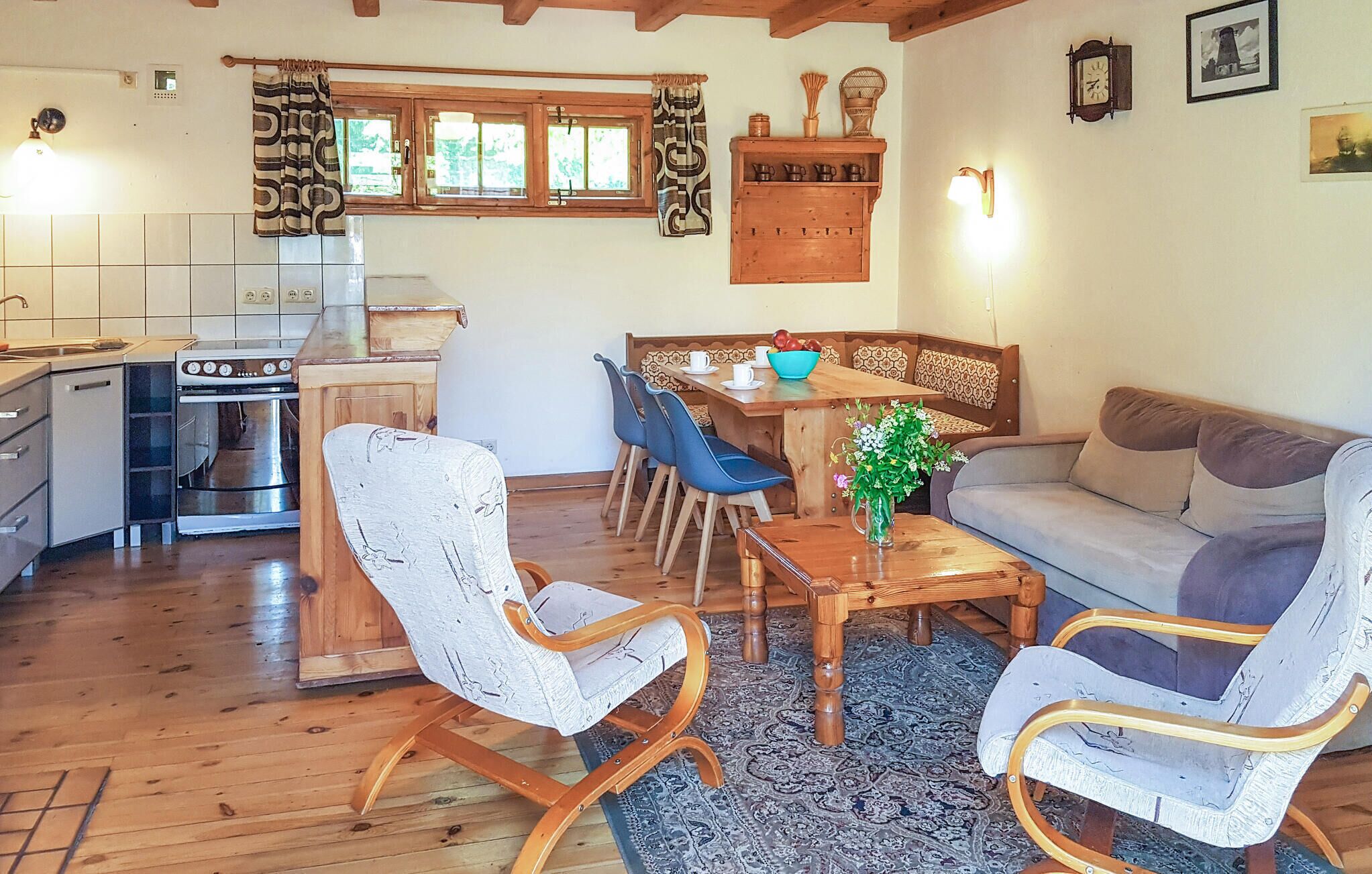 Un salon confortable avec un canapé, des fauteuils, une table à manger et un coin cuisine équipé d’une cuisinière et de placards.