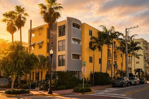 A multi-story hotel with a curved facade, palm trees, and a street view with parked cars.