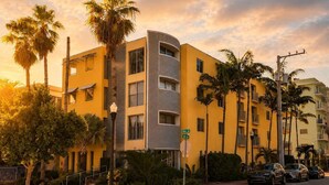 A multi-story hotel with a curved facade, palm trees, and a street view with parked cars. - Walk to Beach- South of Fifth Condo | Free Parking (Miami Beach)