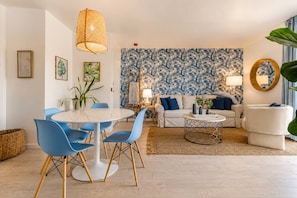 Un salon moderne avec une table à manger ronde, des chaises bleues, un canapé et un papier peint à motifs.