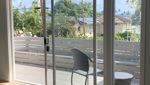 Une pièce dotée d’une porte-fenêtre coulissante donnant sur un balcon avec une chaise et une petite table.
