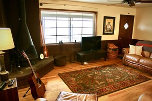 A living room with a fireplace, television, leather sofa, and a large window.