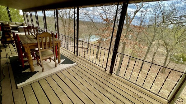A wooden deck with a railing, a sofa, and a chair.