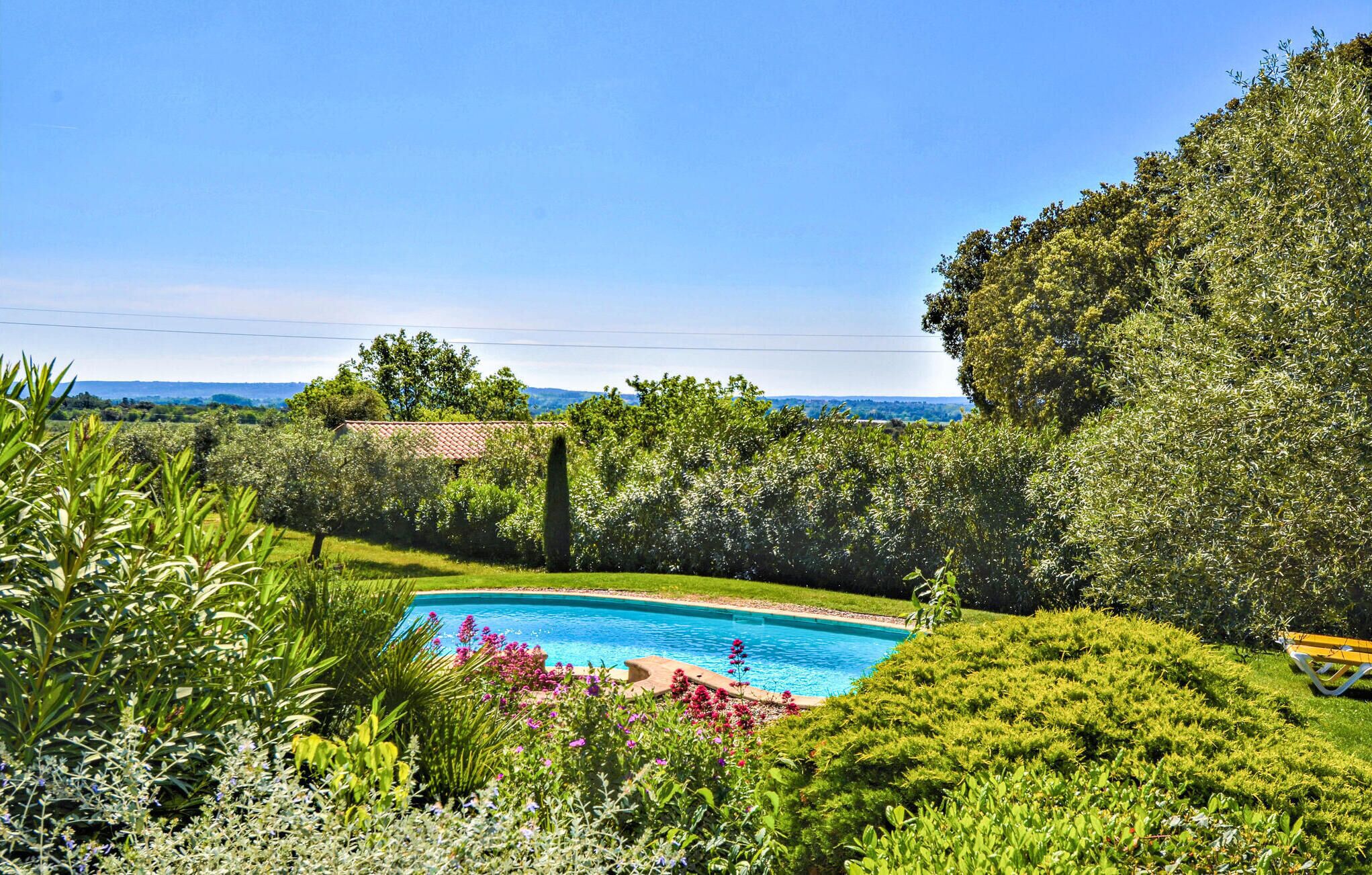 Une piscine entourée d’une végétation luxuriante, avec vue sur la mer.