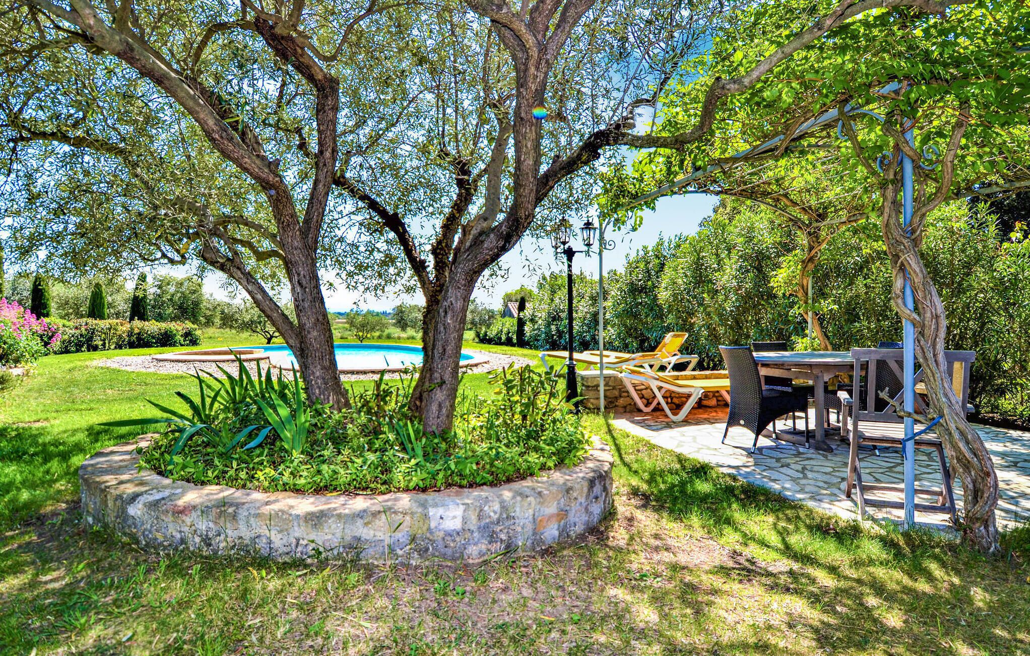 Un jardín con piscina, mobiliario exterior y una pérgola.