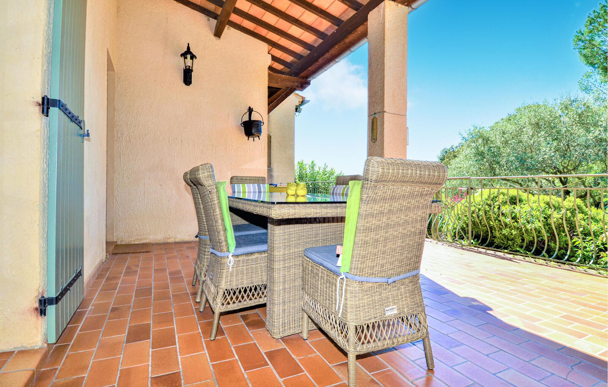 A covered patio with wicker furniture, a table, and two chairs.