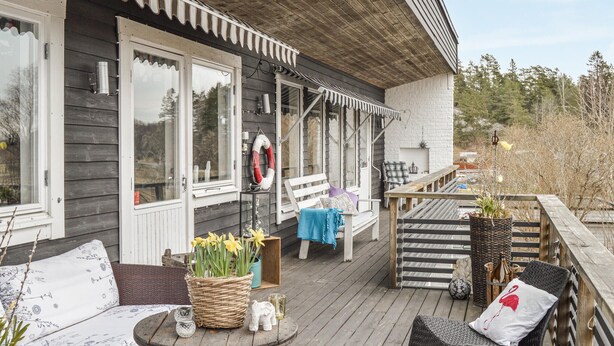 A wooden deck with a bench, a wicker basket with flowers, and a railing. - Pet friendly home in Trosa with sauna (Trosa)