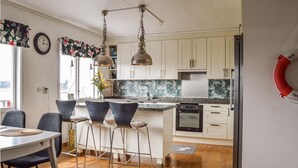 A modern kitchen with white cabinets, a central island, and bar stools. - Pet friendly home in Trosa with sauna (Trosa)