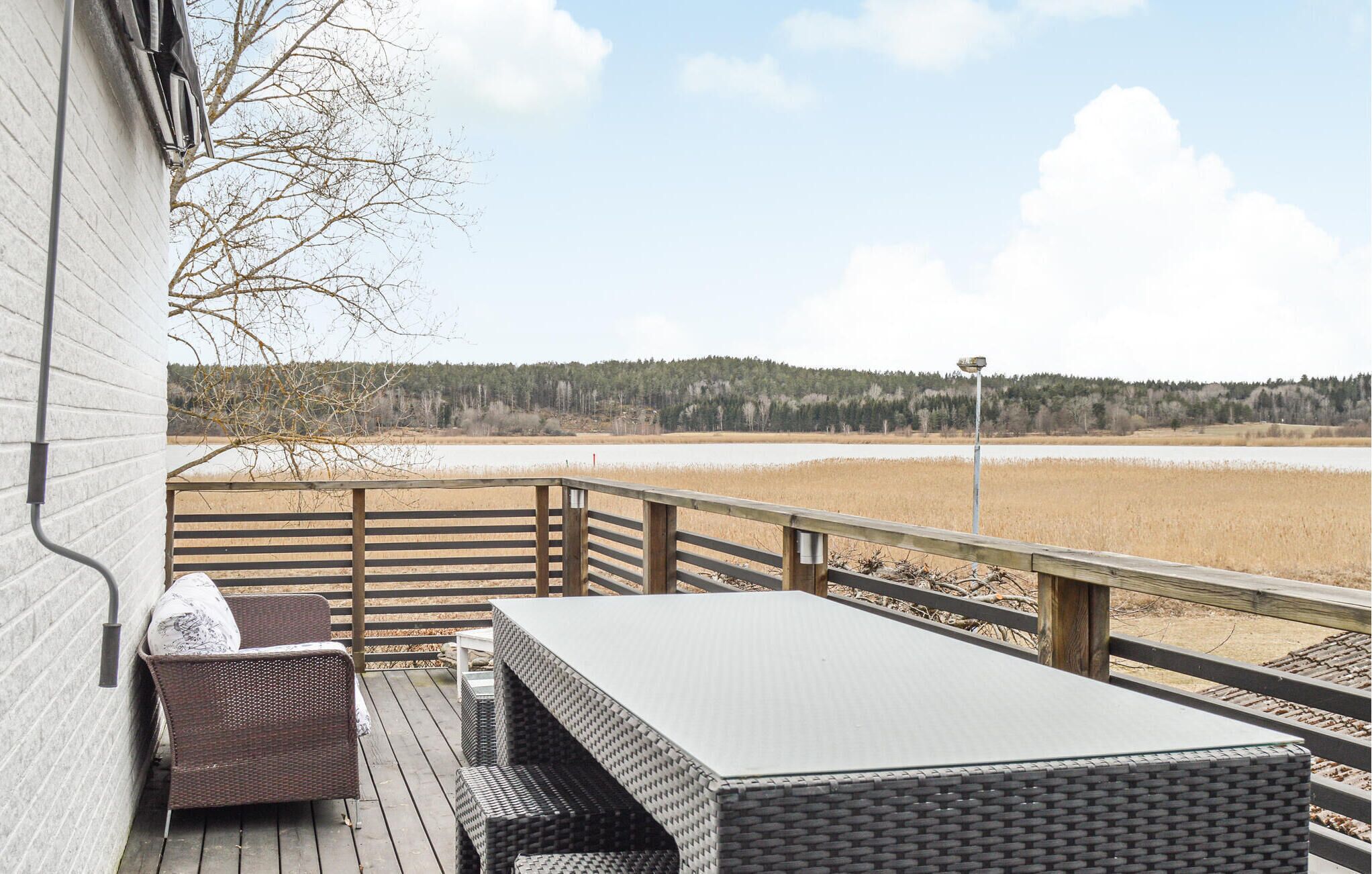 En terrass med utem öbler och utsikt över en sjö och en skog.