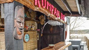 A rustic bar with wooden walls, a wooden face carving, a clock, and various bottles and glasses. - Pet friendly home in Trosa with sauna (Trosa)
