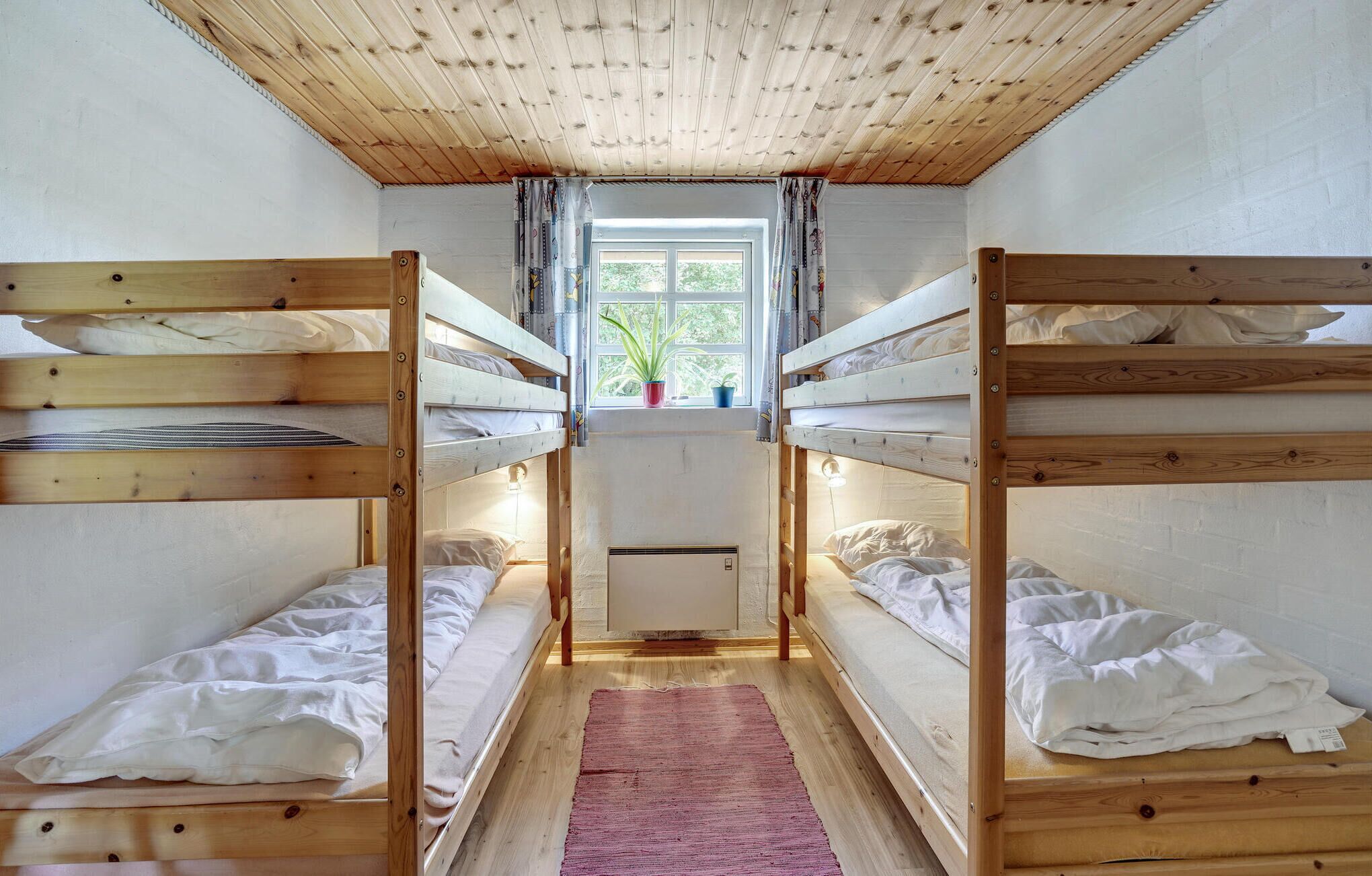 Quarto com beliches, janela com cortinas e radiador.