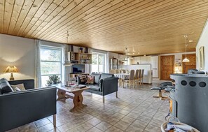 A spacious living area with a fireplace, a dining table, and a kitchen in the background. - Stunning home in Ulfborg with kitchen (Ulfborg)