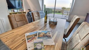 Een eetgedeelte met een houten tafel, brochures en een fles wijn.