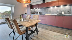Een moderne keuken met een eetgedeelte, met een houten tafel en stoelen, een groot raam en uitzicht op het omliggende landschap.