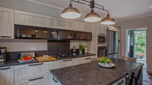 Una cocina moderna con armarios de madera clara, una isla central y electrodomésticos de acero inoxidable.