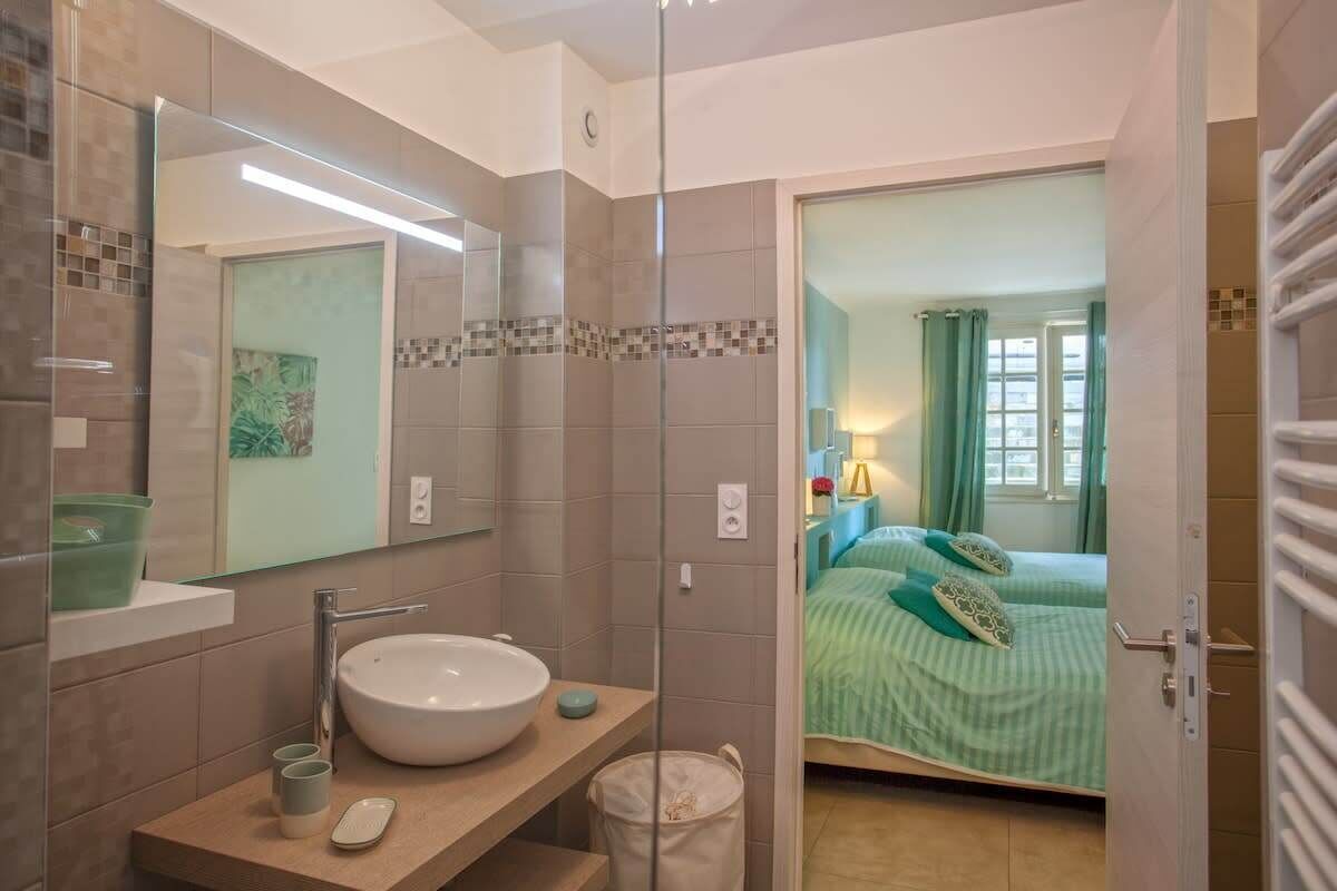 A bathroom with a large mirror, a sink, and a shower.
