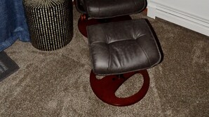 A dark brown leather recliner with a footrest and a round ottoman beside it. - Quaint updated apartment overlooking the Bay (Washburn)