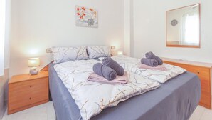 A neatly made bed with a patterned bedspread, two pillows, and two rolled towels on the bed. - 2 bedroom gorgeous apartment in Torrevieja (Torrevieja)