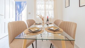 A dining table set for four with beige chairs, a glass top, and a vase with dried flowers. - 2 bedroom gorgeous apartment in Torrevieja (Torrevieja)